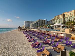 een rij ligstoelen op het strand bij een resort bij Hard Rock Hotel Cancun - All Inclusive in Cancun