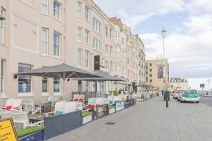a sidewalk with chairs and umbrellas on a city street at King Size Bed Super Morden One Bedroom Flat next to Seafront in Brighton & Hove