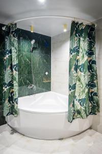 a white bath tub in a bathroom with green tiles at RICH Boutique-Hotel in Vinnytsya