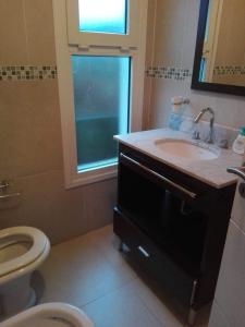 a bathroom with a sink and a toilet and a window at Villa Clarita Tandil in Tandil