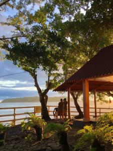 two people and a dog under a gazebo near the water at Hostal Familiar Rolo in Santa Catalina