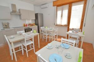 una cucina e una sala da pranzo con tavoli e sedie bianchi di B&B Linae - Residence ad Alba Adriatica