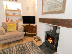 sala de estar con chimenea, sofá y TV en Marlin Cottage en Conwy
