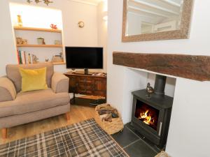 a living room with a fireplace and a couch and a television at Marlin Cottage in Conwy