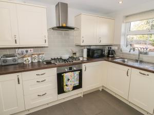 eine Küche mit weißen Schränken und einer Spüle in der Unterkunft Marlin Cottage in Conwy + 10 Fotos