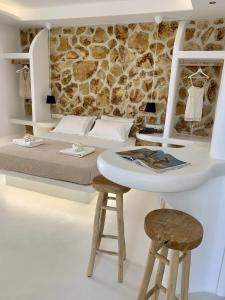 a bedroom with a bed and a table and two stools at Krina Mare Boutique Hotel in Naxos Chora