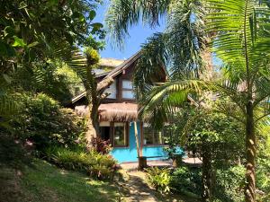 a house with a palm tree in front of it at Pousada Bungalow in Praia do Rosa