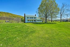 una casa blanca en un campo verde con un árbol en Renovated KY Farmhouse Retreat with Pasture Views! en Wallingford