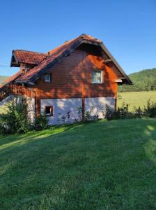 a large wooden house in a field with a grass yard at Vikendica Studenac in Zlatibor