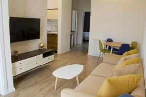 a living room with a couch and a tv and a table at Sameba Bell, Luxury Apartment in Tbilisi City