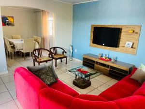 ein Wohnzimmer mit einem roten Sofa und einem TV in der Unterkunft Juventus Residence in Goiânia