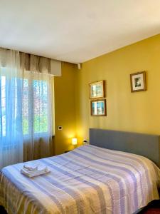 een slaapkamer met een bed met een gestreepte deken en een raam bij Le VELE in Lido di Ostia