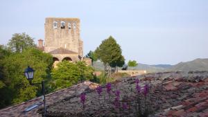 a building with a tower and a stone wall with purple flowers at Casa La Rinconada in Azuelo