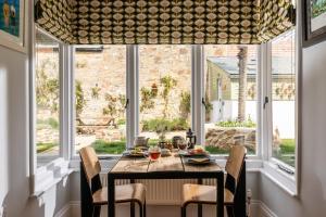 a dining room with a table and chairs and windows at Penwyth House in Newquay