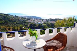 a table with a vase and chairs on a balcony at Rizos Veranda - Rooms in Isómata