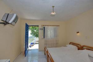 a bedroom with a bed and a tv on the wall at Rizos Veranda - Rooms in Isómata