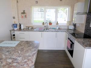 Beautiful 3-Bed Cottage in Cornwall في Callington: مطبخ مع خزائن بيضاء وقمم من الجرانيت