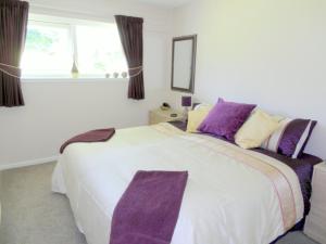 a bedroom with a large white bed with purple pillows at Beautiful 3-Bed Cottage in Cornwall in Callington