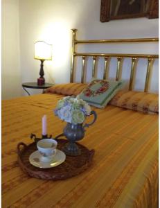 una bandeja con una vela y un jarrón con flores en una cama en Le case nel borgo Crucoli (2), en Crucoli