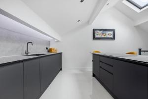 a kitchen with black cabinets and white floors at Winter Garden Apartments by Sasco in Blackpool