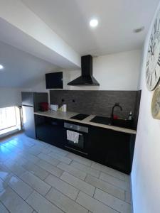 a kitchen with a sink and a clock on the wall at Love’Room in Trèbes