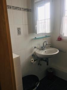 a white bathroom with a sink and a window at Apartment am Rathaus in Rödermark