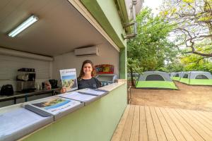 a woman standing behind a counter with tents in the background at Camping Dafna - By Travel Hotel Chain in Metsudat Menahem Ussishkin Alef