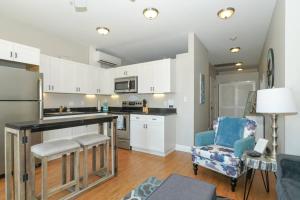 a kitchen with white cabinets and a blue chair at Siesta Cool: Only Minutes Walk to Siesta Beach! in Siesta Key