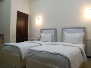dos camas sentadas una al lado de la otra en una habitación en Queens Hotel en Tashkent