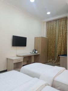 1 dormitorio con 2 camas y escritorio con TV en Queens Hotel en Tashkent