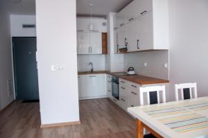 a kitchen with white cabinets and a table at JGJ Ostoja in Puck