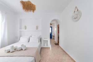 a white bedroom with two beds and a hallway at sunsetview1 studios in Batsi