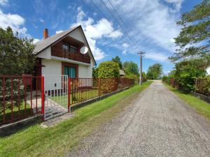 una casa con una valla roja en un camino de tierra en Vitorlás Haus, en Balatonkeresztúr