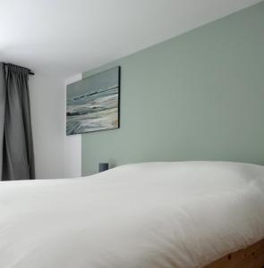 Surf & Kite - Villa Nortada في تشارنكه: سرير أبيض في غرفة نوم مع لوحة على الحائط