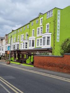 Une rangée de bâtiments verts et blancs dans une rue dans l'établissement The Lawton, à Blackpool