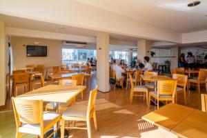 a restaurant with wooden tables and chairs and people sitting at tables at Bristol Condominio Apart Hotel in Mar del Plata