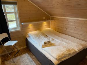 Cama en habitación de madera con silla en Flott sjøhus rett ved Saltstraumen, en Saltstraumen