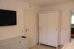 a bedroom with a white cabinet and a flat screen tv at Schöne Ferienwohnung vor den Toren Pullman Citys zwei in Aicha vorm Wald