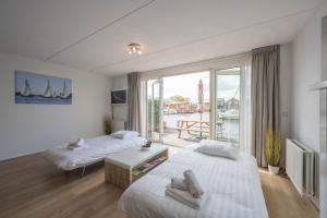 UitgeestにあるMeerzicht 70 - Vakantiehuis aan het water!の大きな窓のある部屋にベッドが2つある