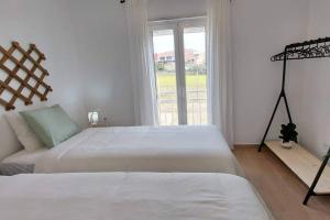 ein weißes Schlafzimmer mit zwei Betten und einem Fenster in der Unterkunft Casa 37 - Country Home in Terrugem