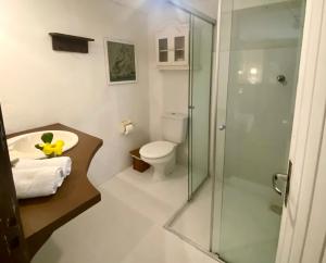 a bathroom with a toilet and a glass shower at Pousada Bungalow in Praia do Rosa