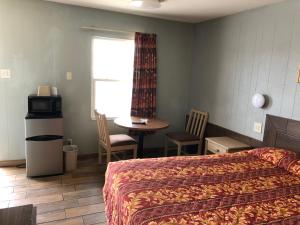 a bedroom with a bed and a table and a window at Budget inn in Kingsville