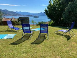 three chairs and a table in the grass near a lake at Armonie del Lago in Baveno