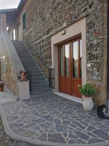 un chat assis à côté d'un bâtiment en briques avec une porte en bois dans l'établissement Castelvecchio B&B, à Sorano