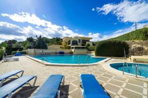 een zwembad met blauwe stoelen en een huis bij 4 persoons bungalow met gemeenschappelijk zwembad in Teulada