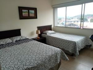 a bedroom with two beds and a large window at Hotel Doral in Panama City