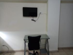 a desk with a chair and a television on a wall at Hotel Doral in Panama City