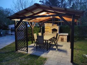 a wooden pavilion with a table and chairs and a fireplace at Willa Dilla in Ustronie Morskie