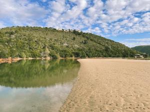 a beach with a hill in the background and a body of water at Leisure Isle Loft Apartment in Knysna +5 photos