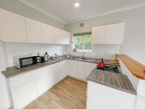 a kitchen with white cabinets and a sink and a microwave at Leisure Isle Loft Apartment in Knysna